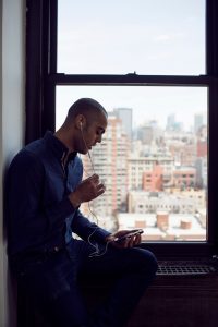Businessman using phone while sitting at window sill