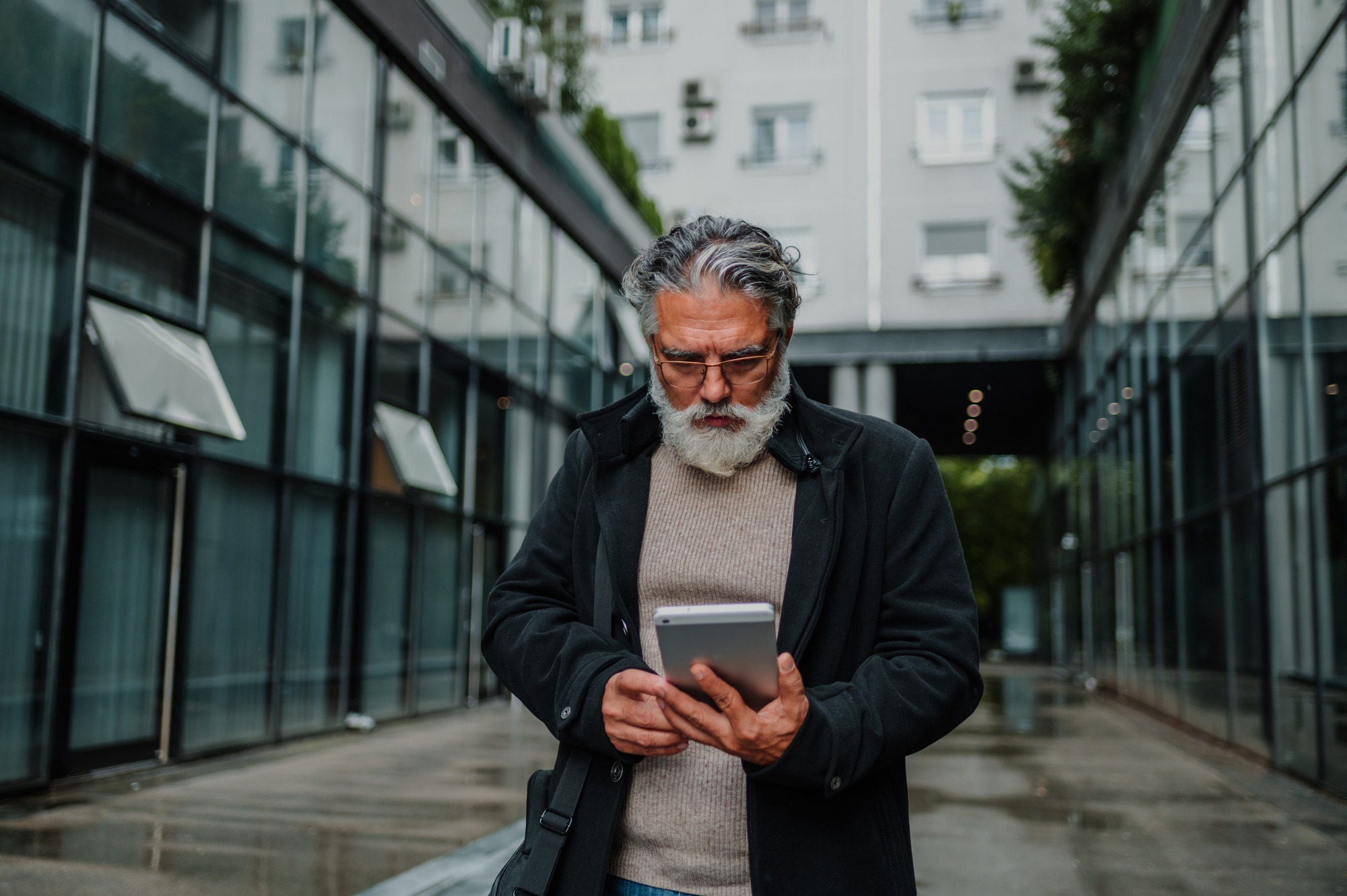 Portrait of a senior businessman using tablet outside of the office building